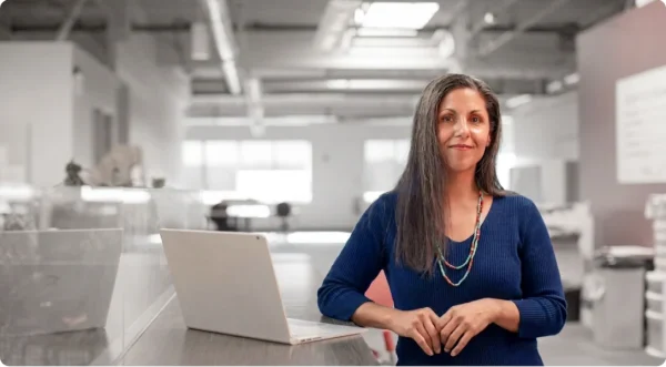 Person seated at a desk with a laptop in a modern office.